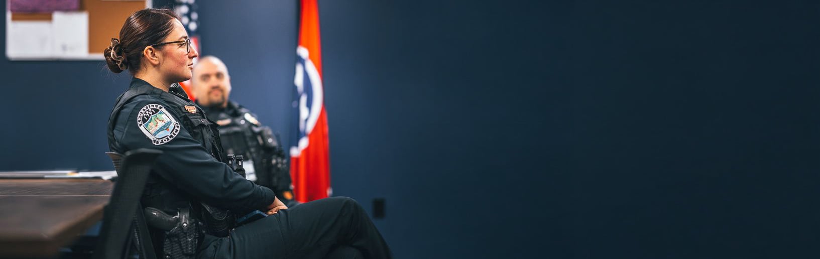 Police officers seated in a training classroom with a Tennessee state flag in the background