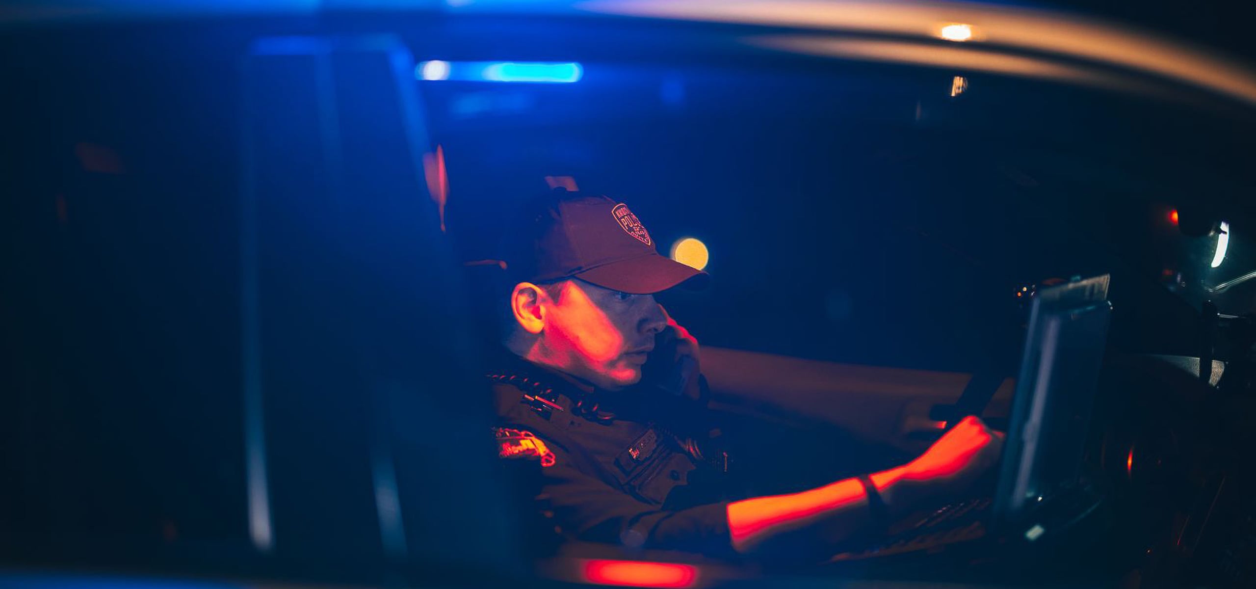 Law enforcement officer using a computer in a police vehicle at night