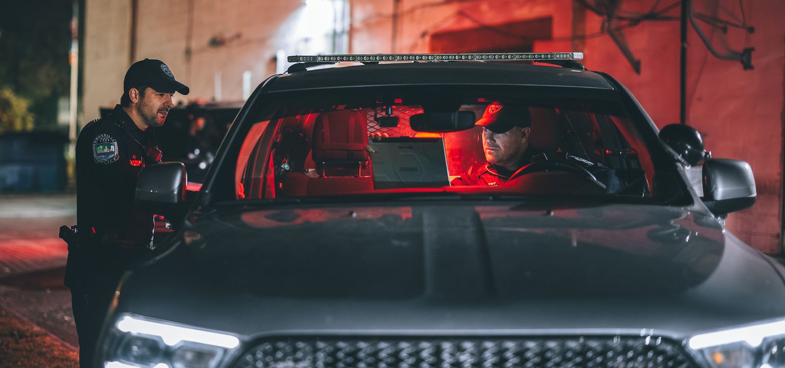 Law enforcement officers working in a patrol car at night