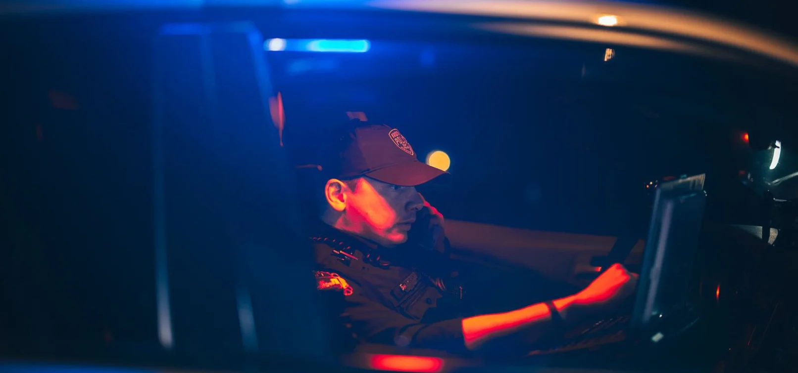 Law enforcement officer using a computer in a police vehicle at night